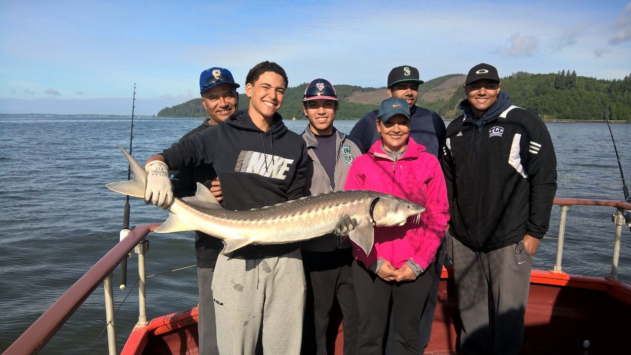 A group of people are standing on a boat holding a large fish.