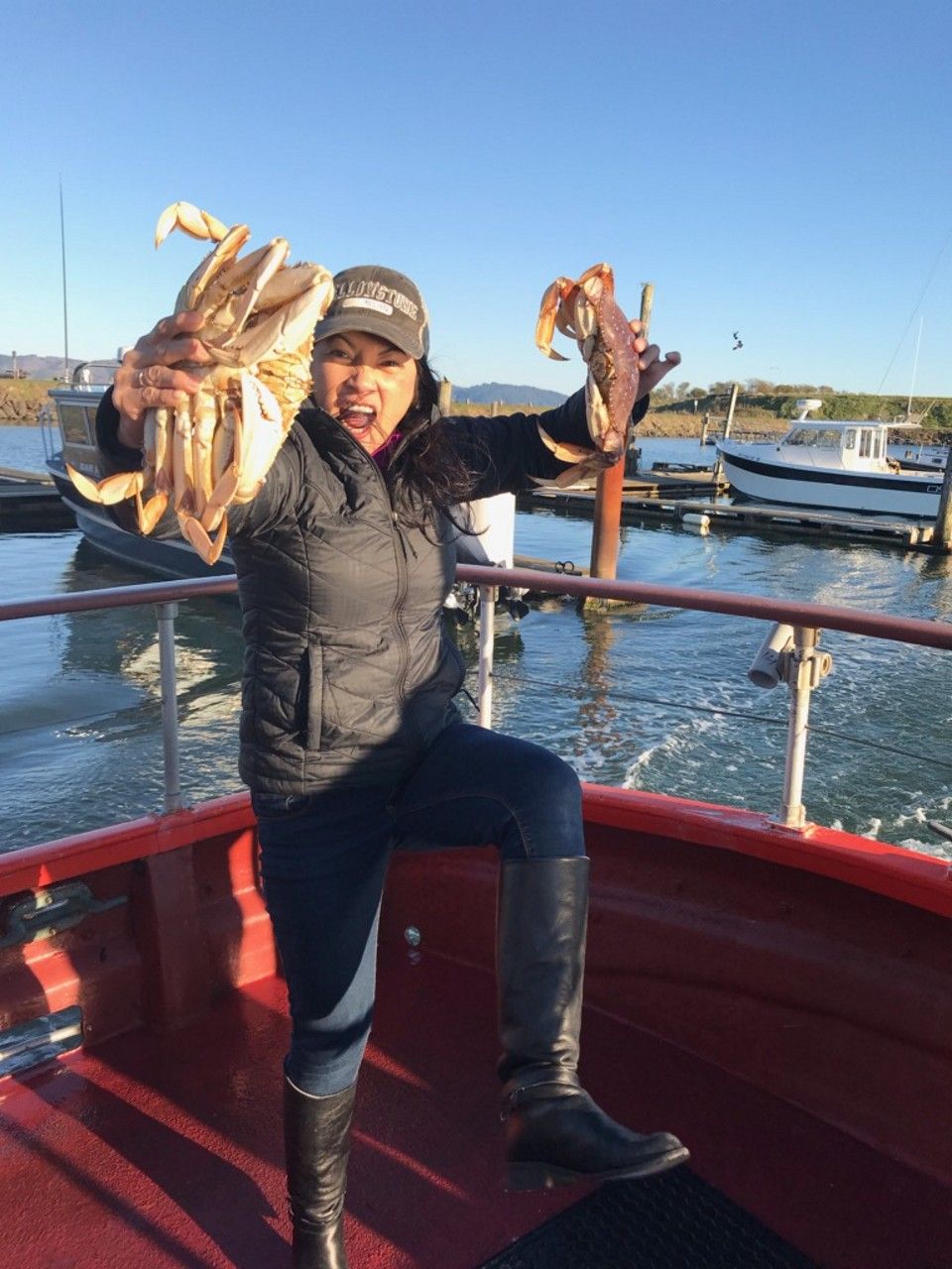 A woman is holding a large crab on a boat.