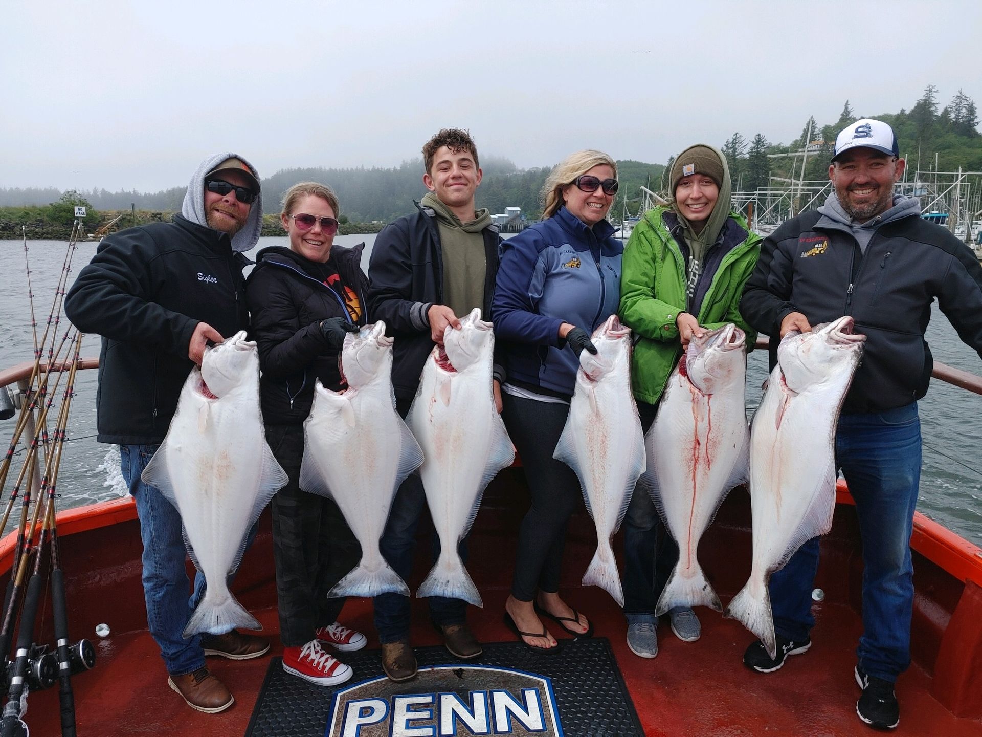 A group of people are standing on a boat holding large fish.
