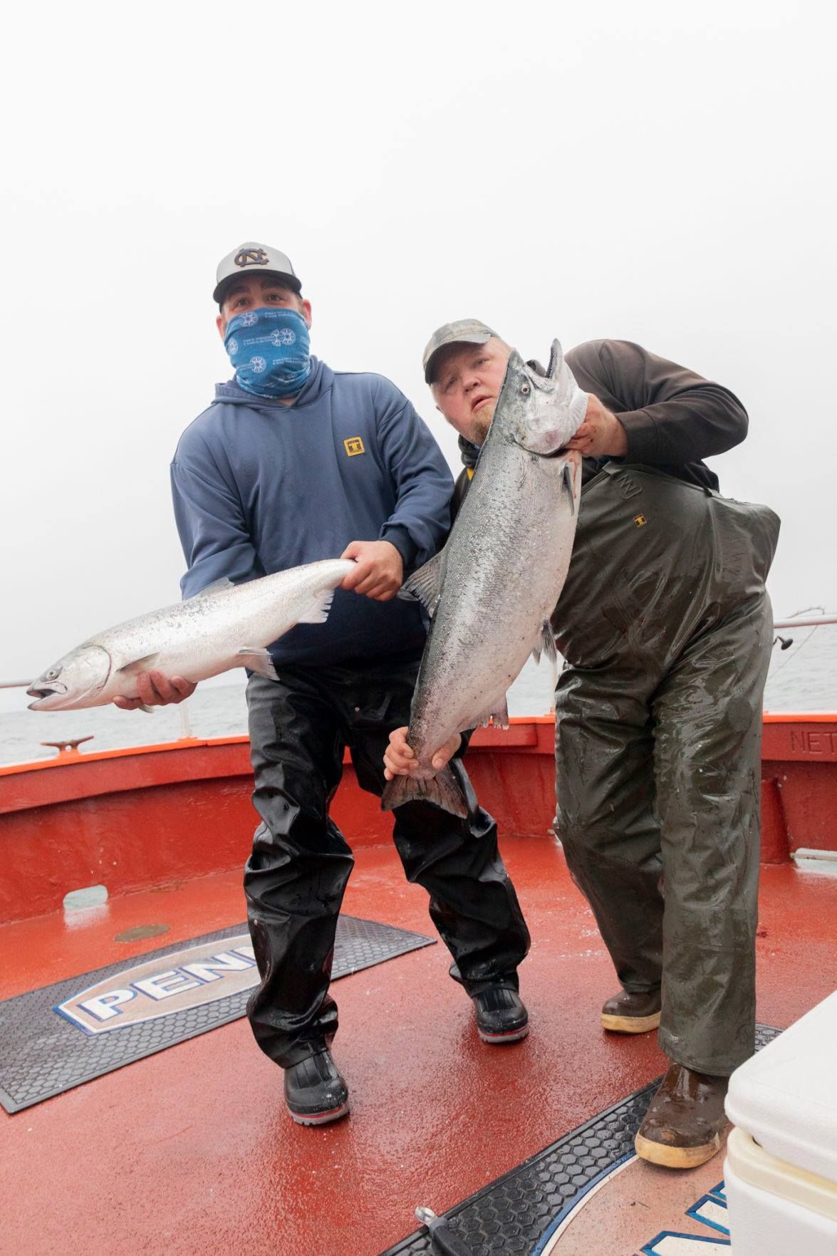 Two men are holding a large fish on a boat.