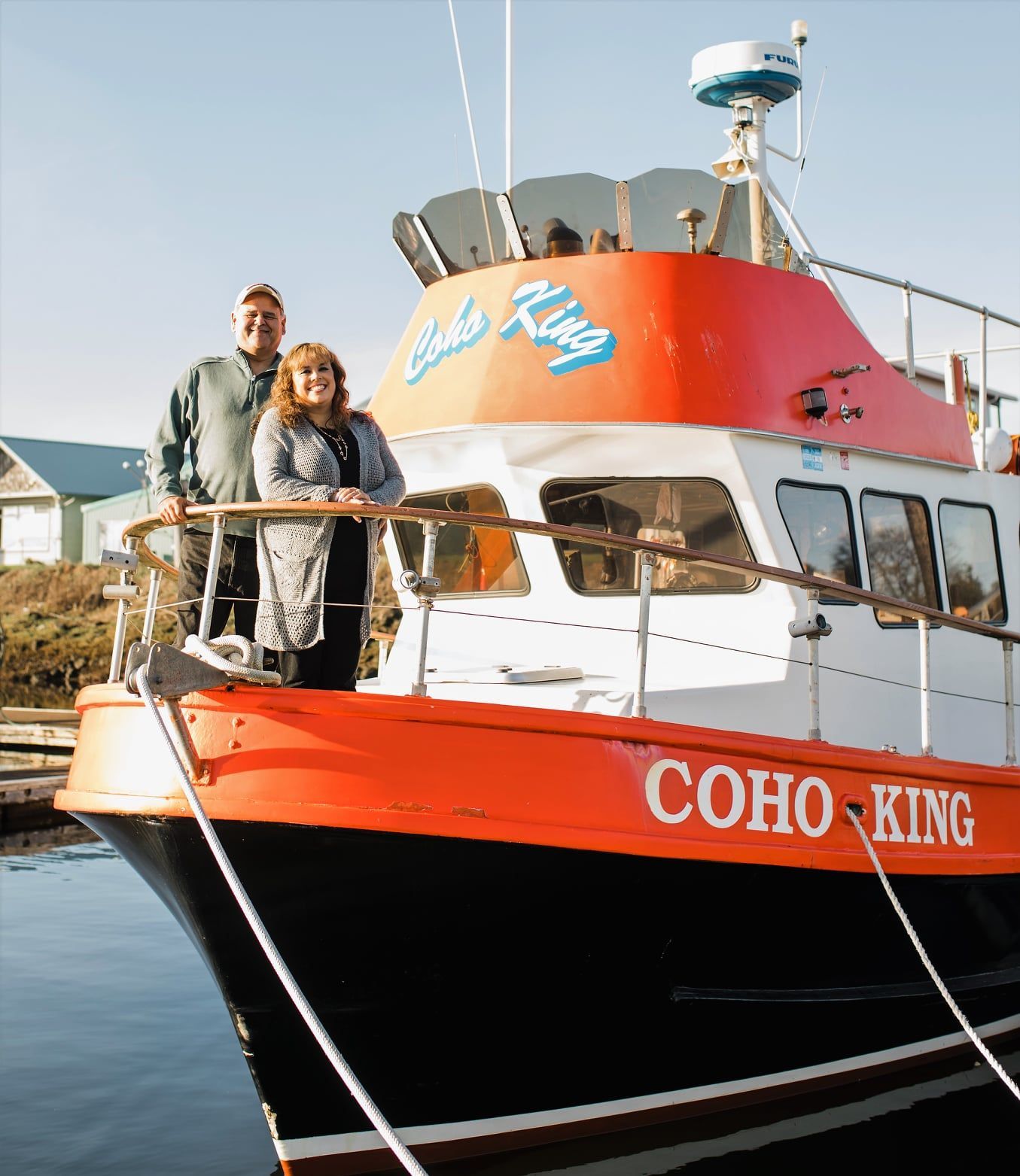 A couple standing on the deck of a coho king boat