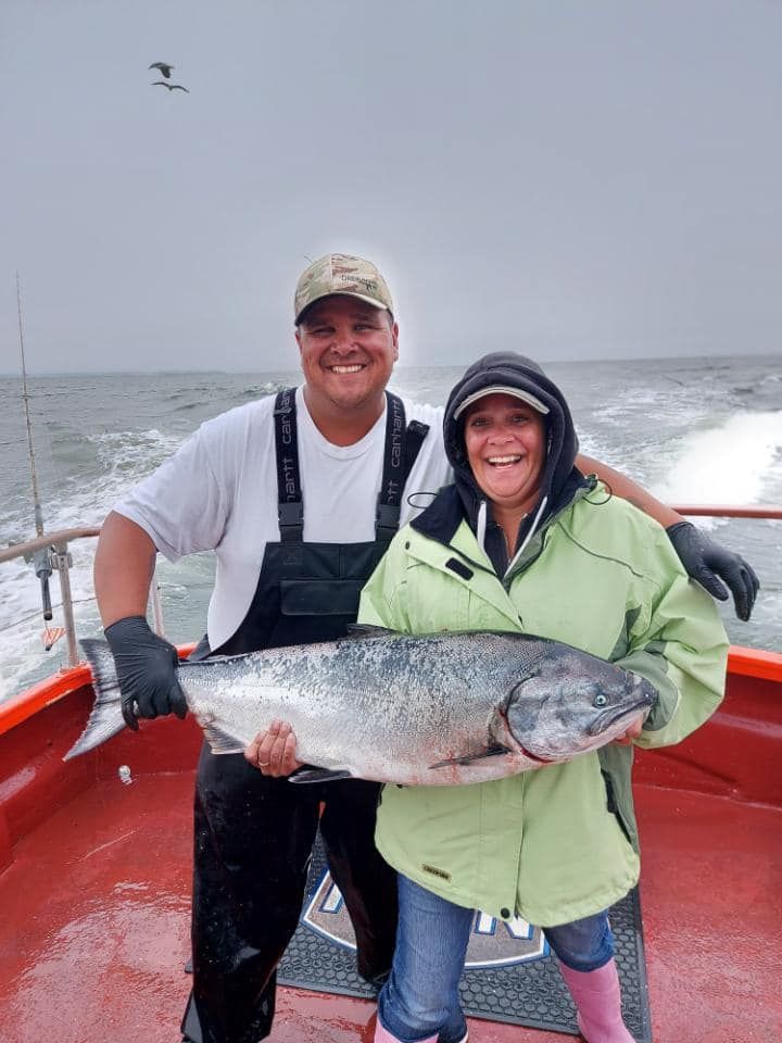 A man and a woman are holding a large fish on a boat.