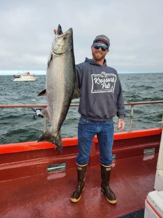 A man is holding a large fish on a boat.