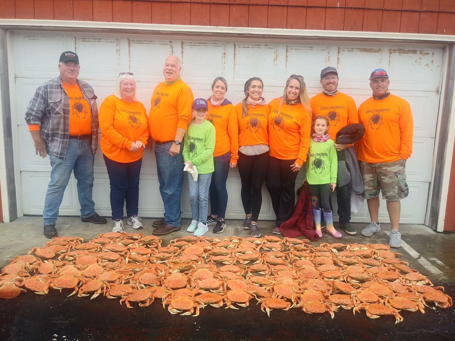 A group of people standing next to a pile of crabs.