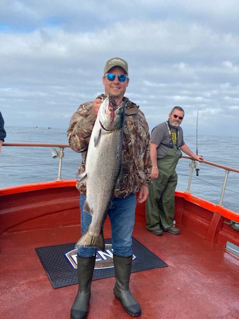 A man is holding a large fish on a boat.