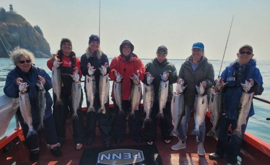 A group of people holding fish on a boat that says penn