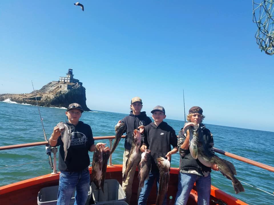 A group of people are standing on a boat holding fish.