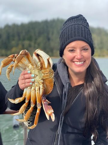 A woman is holding a large crab in her hands and smiling.