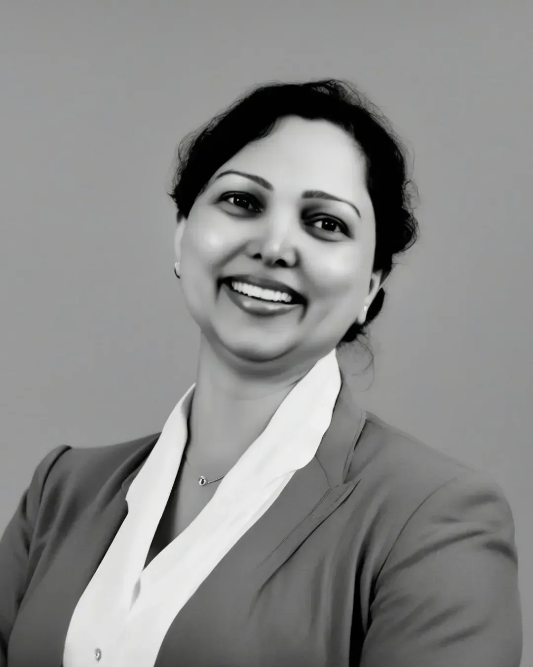 Smiling person in a white scarf and dark blazer against a gray background