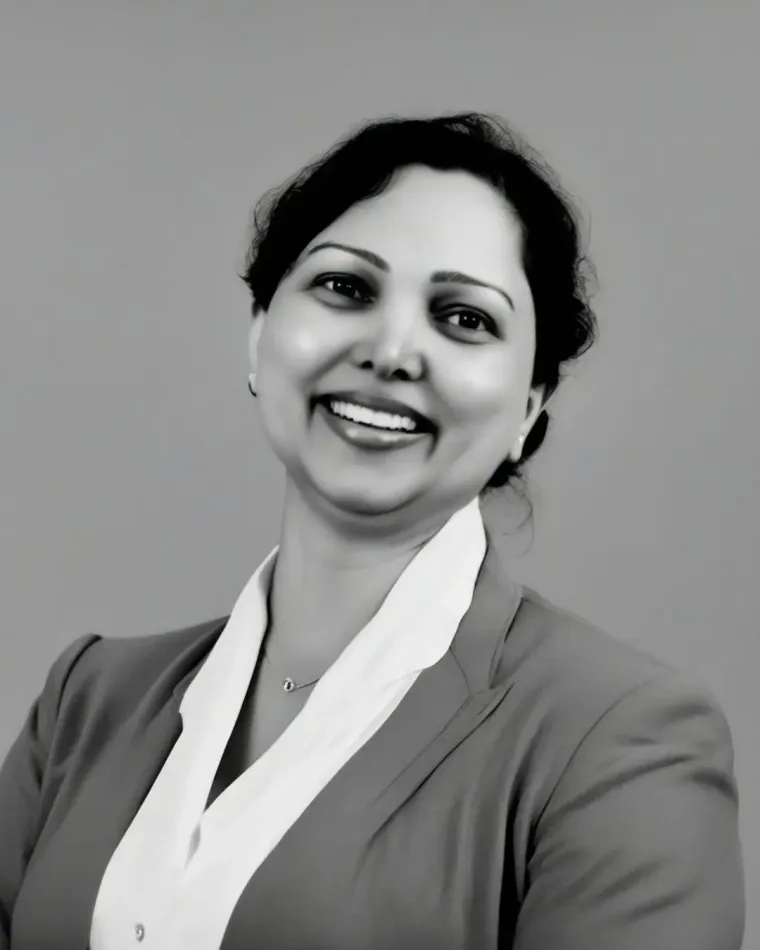 Smiling person in a white scarf and dark blazer against a gray background