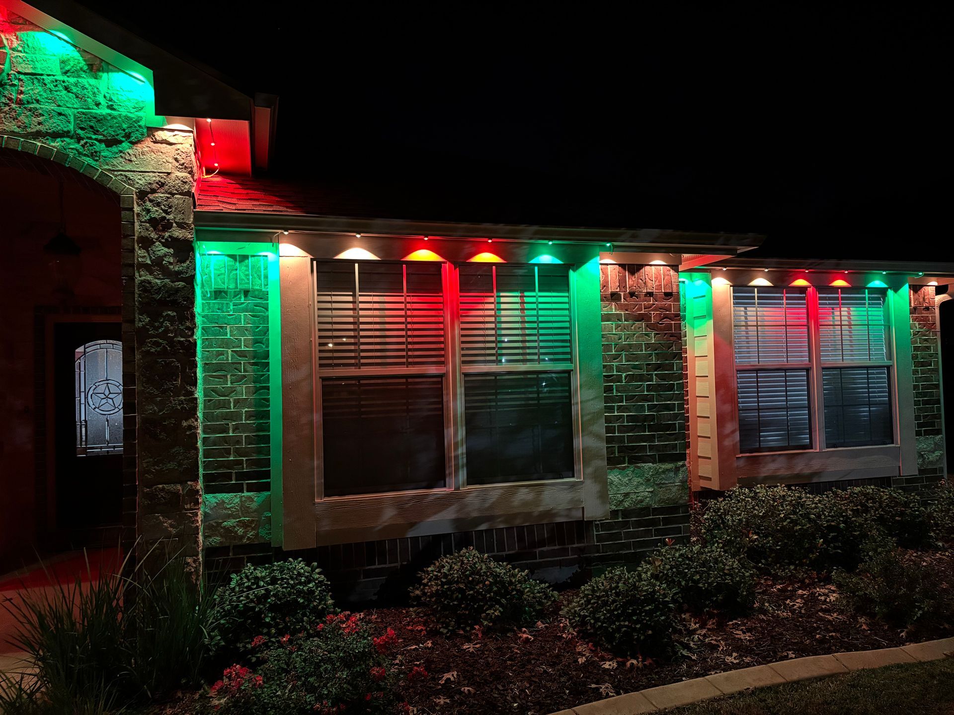 Building exterior lit with red and green holiday lights at night