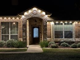 Brick house exterior at night with lit entryway and front walkway