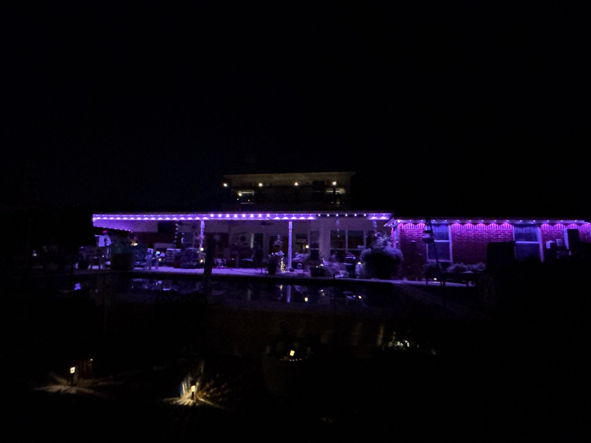 Nighttime view of a building lit with purple lights over dark water