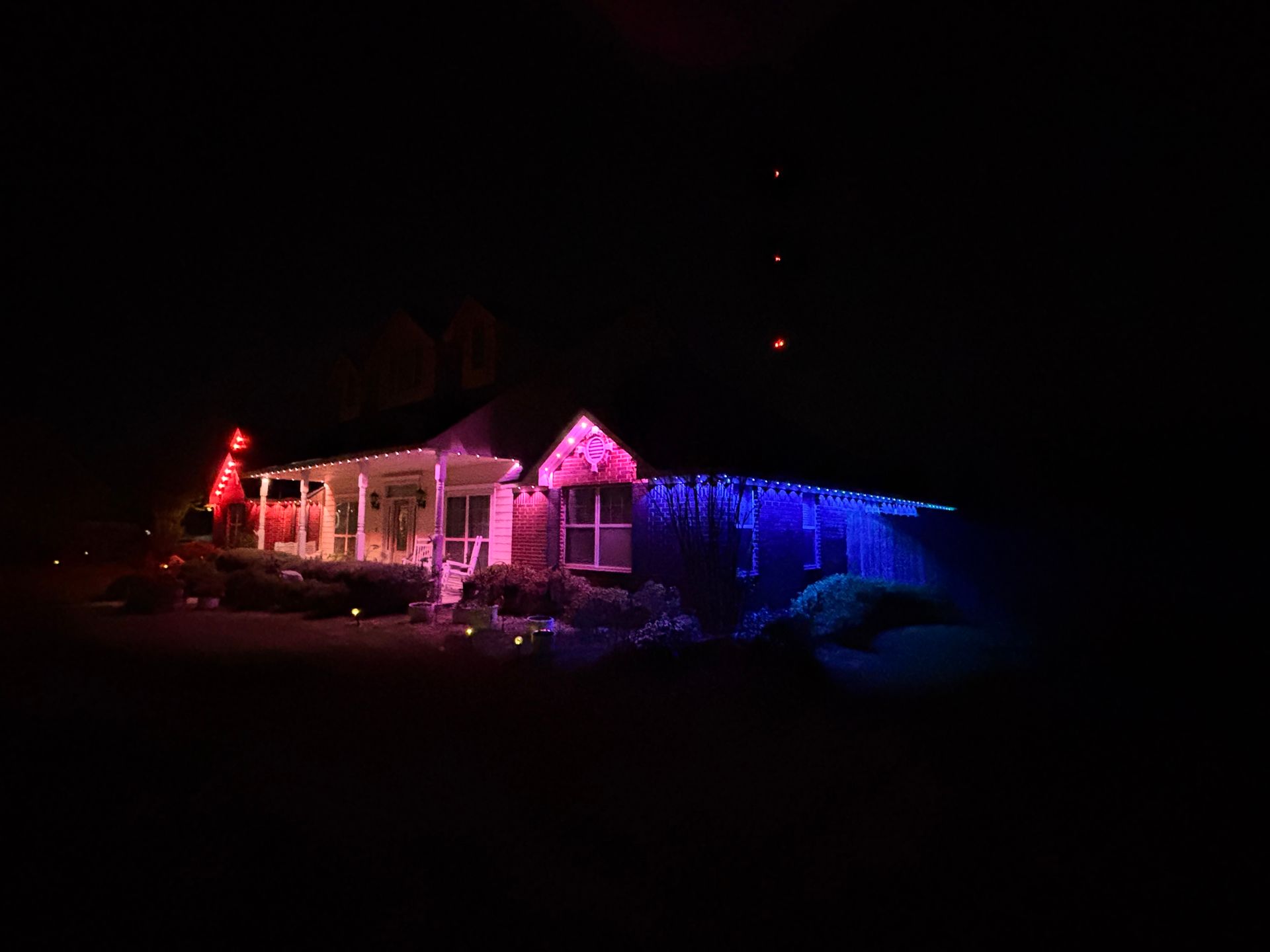 House lit with pink and blue holiday lights at night