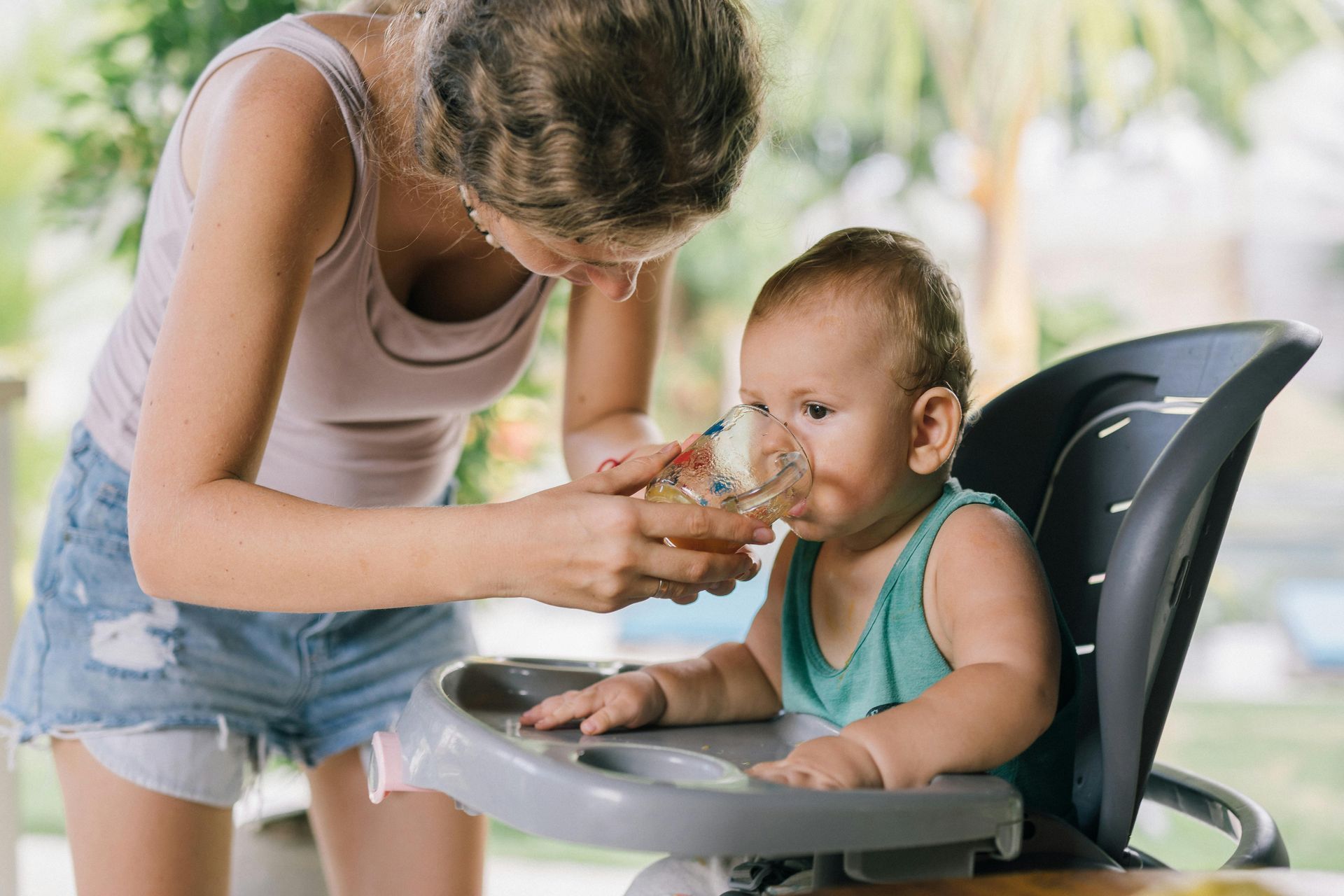 A woman is feeding a baby in a high chair.