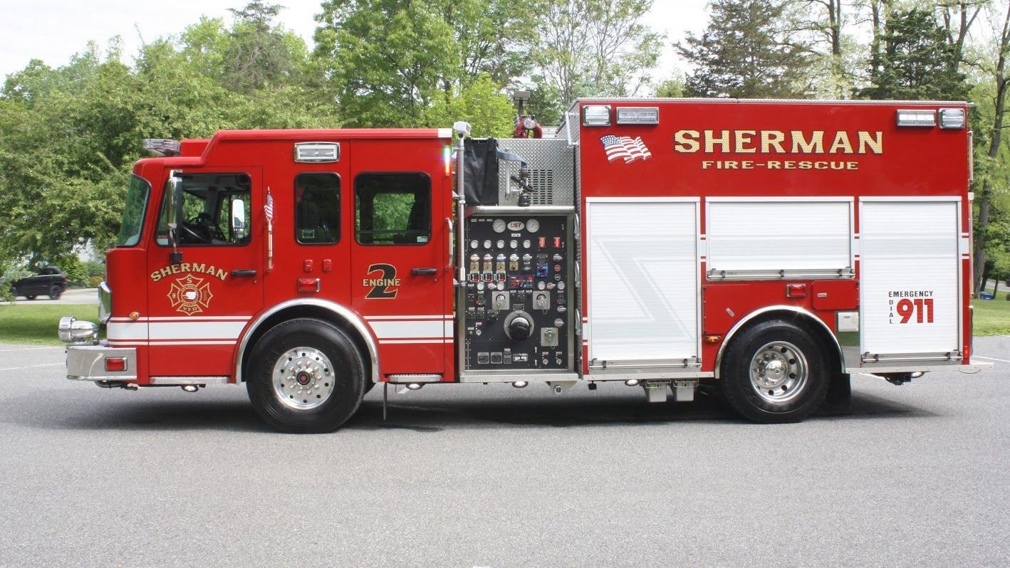 A red sherman fire truck is parked on the side of the road