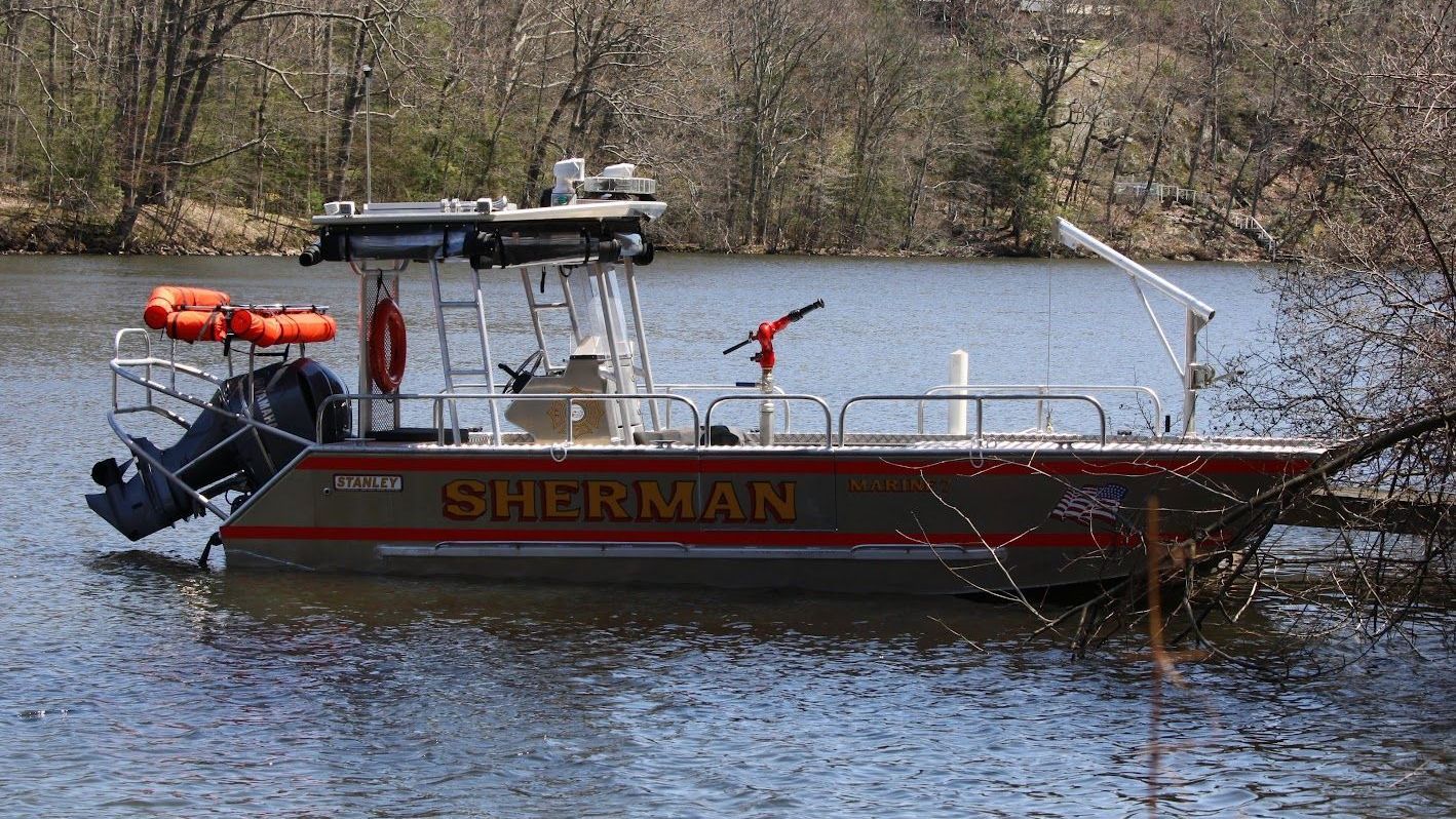 A sherman boat is floating on top of a body of water