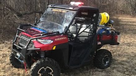 A red atv is parked in the middle of a field.