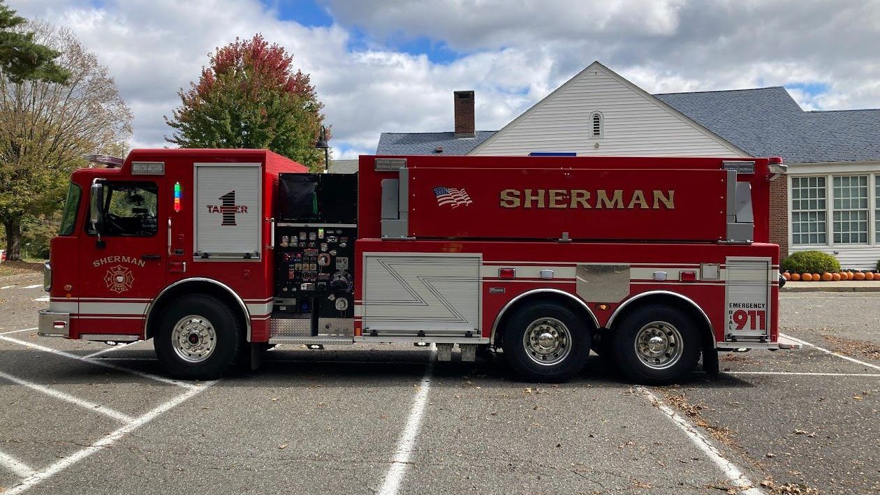A red sherman fire truck is parked in a parking lot