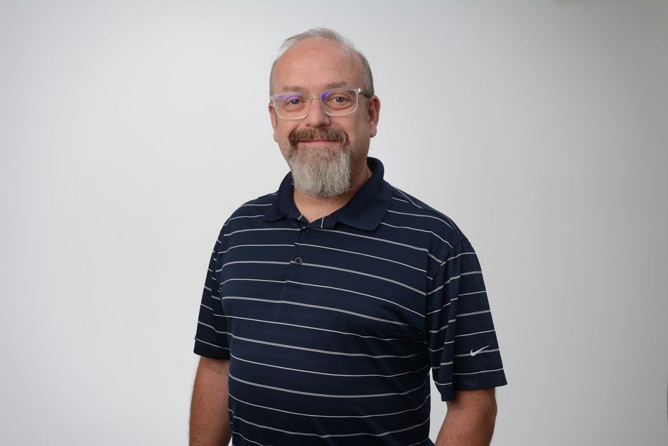 A man with a beard and glasses is wearing a striped shirt.