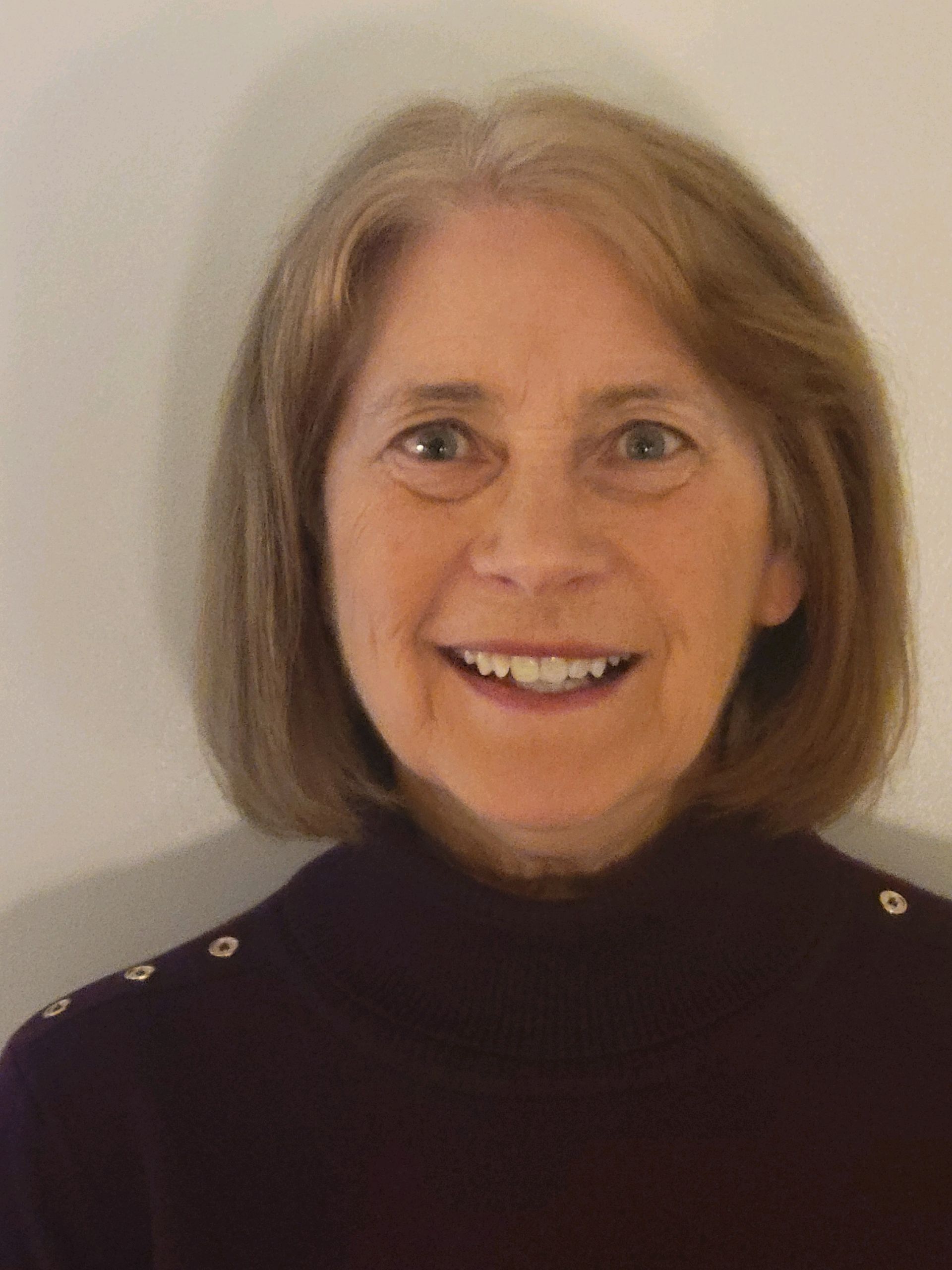 A woman in a purple sweater is smiling for the camera.