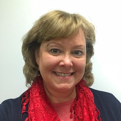 A woman wearing a red scarf and a red shirt is smiling for the camera.