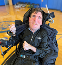 A man is sitting in a wheelchair on a basketball court.