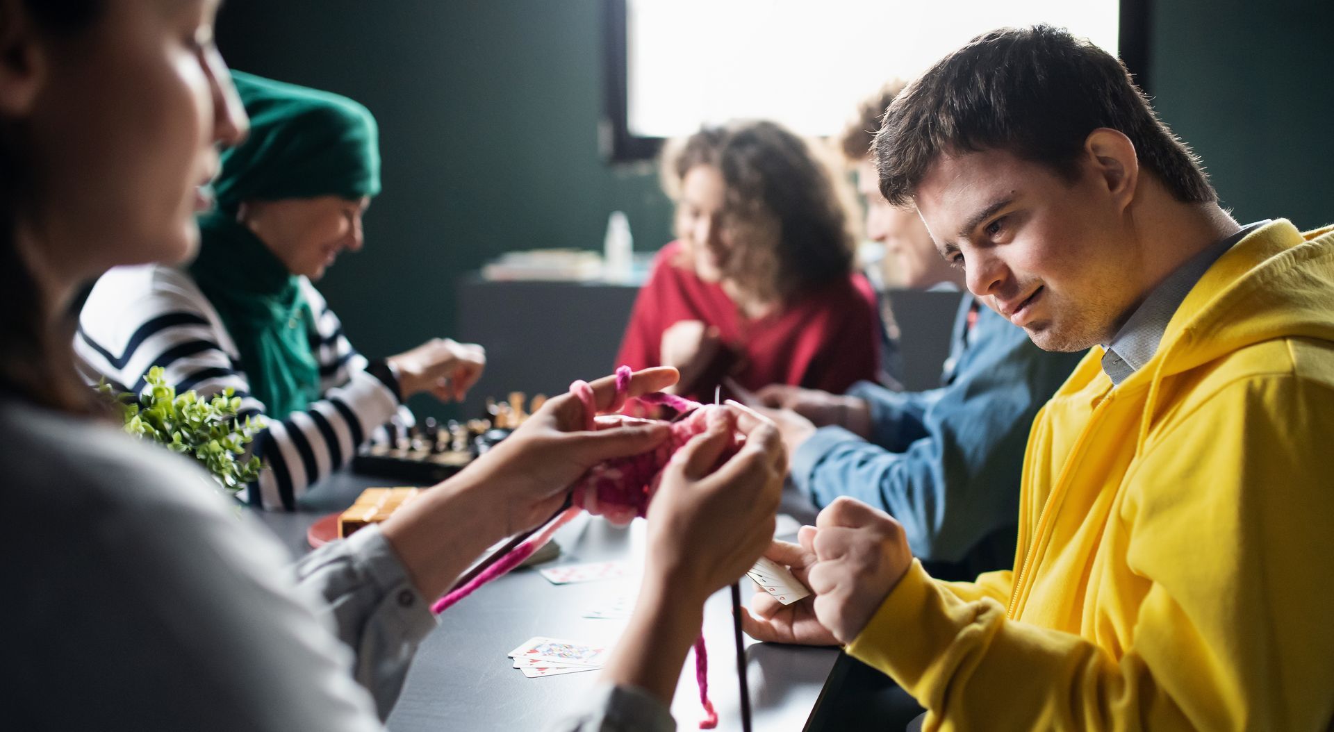 A group of people are sitting around a table knitting.