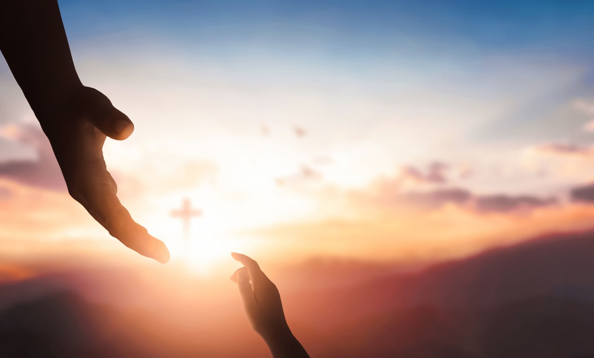 A person is holding another person 's hand in front of a sunset.