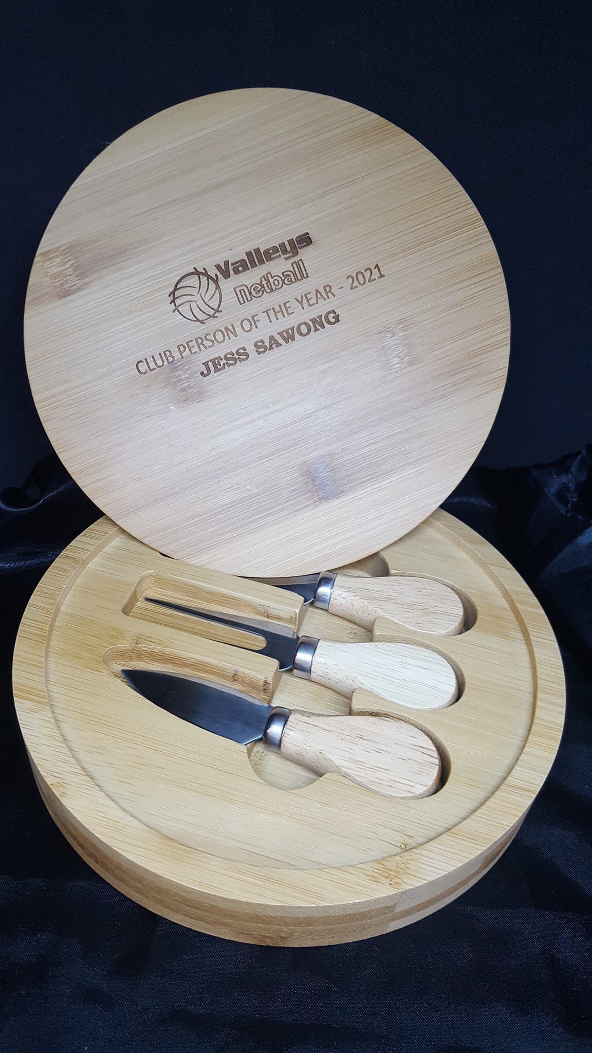 A wooden box with three knives inside of it.