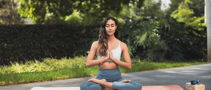 A woman meditating in nature, highlighting the mind-body connection and the power of thought and emotion in health
