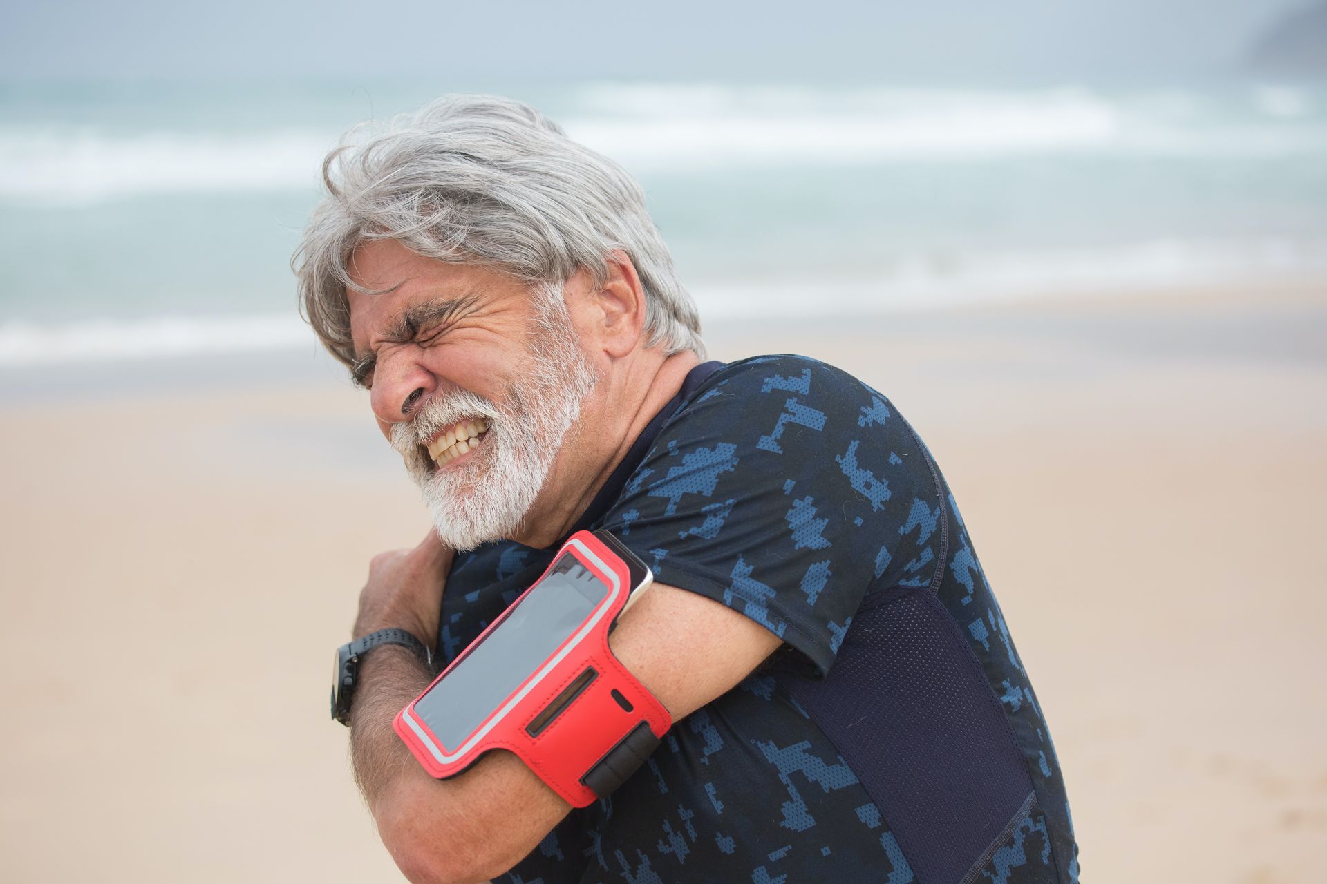 An elderly man in holding his shoulder in pain