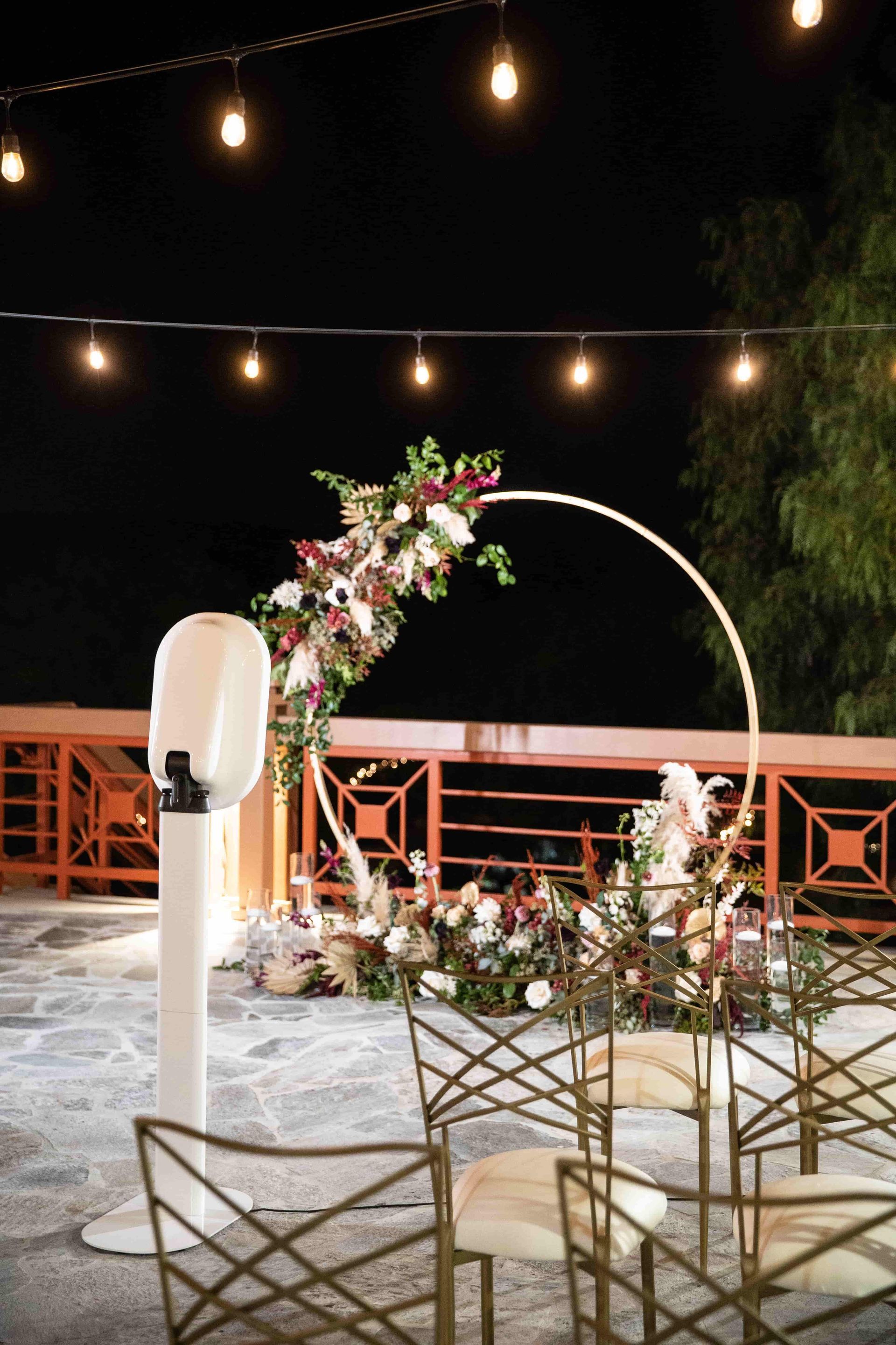 Digital photo booth in front of golden arch with flowers