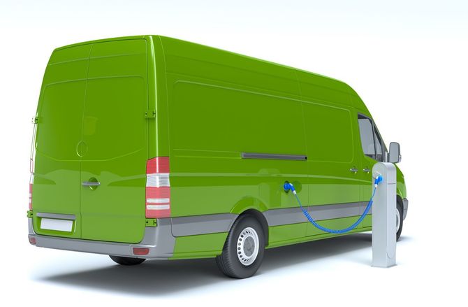 a green electric van is charging at a charging station .