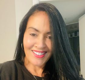 A woman with long black hair is smiling for the camera.