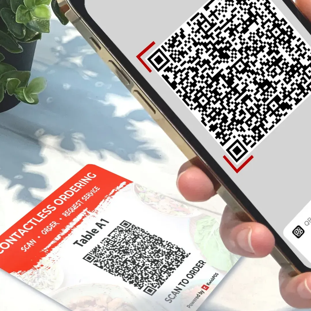 ZBS POS QR code contactless ordering close up of hand holding mobile phone scanning table QR code to order and pay for meal