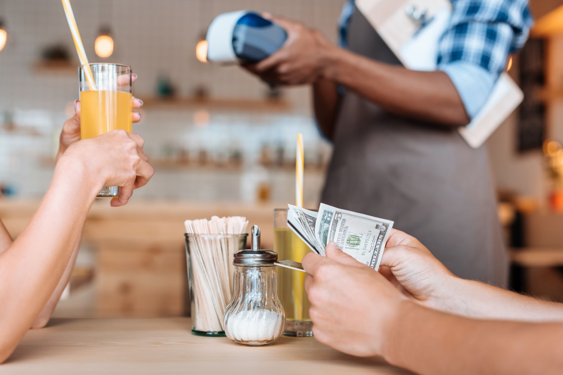customer counting cash at restaurant table, paying for check