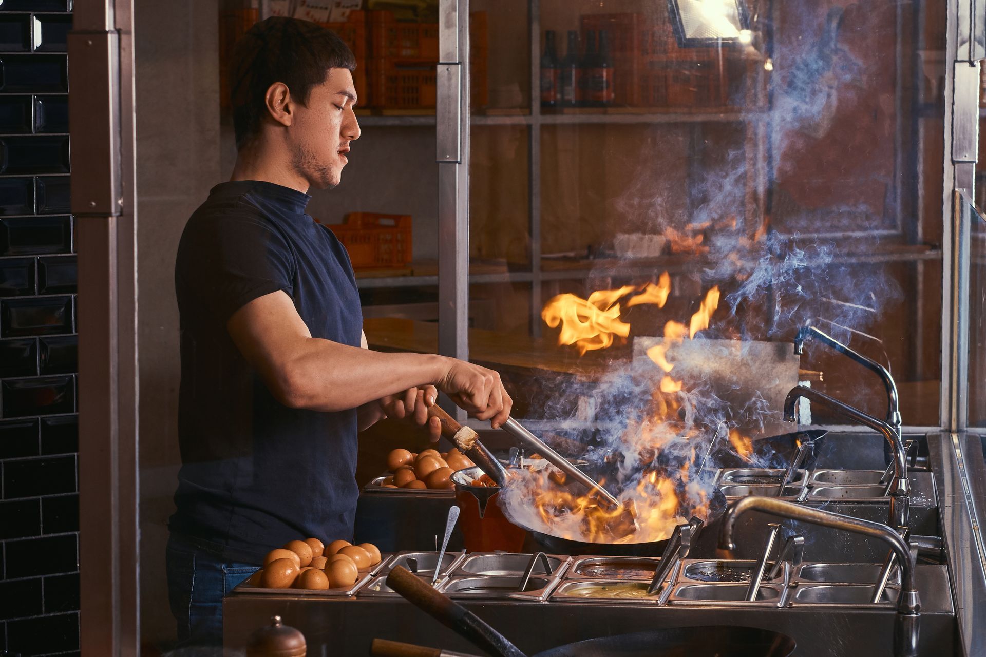 ZBS POS GDC POS Asian chef using a wok to stir fry a dish in a restaurant kitchen for take out order