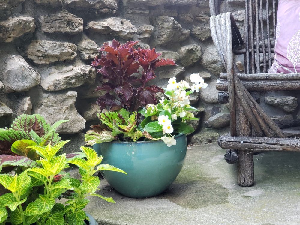 A blue pot filled with flowers is sitting on a patio next to a chair.