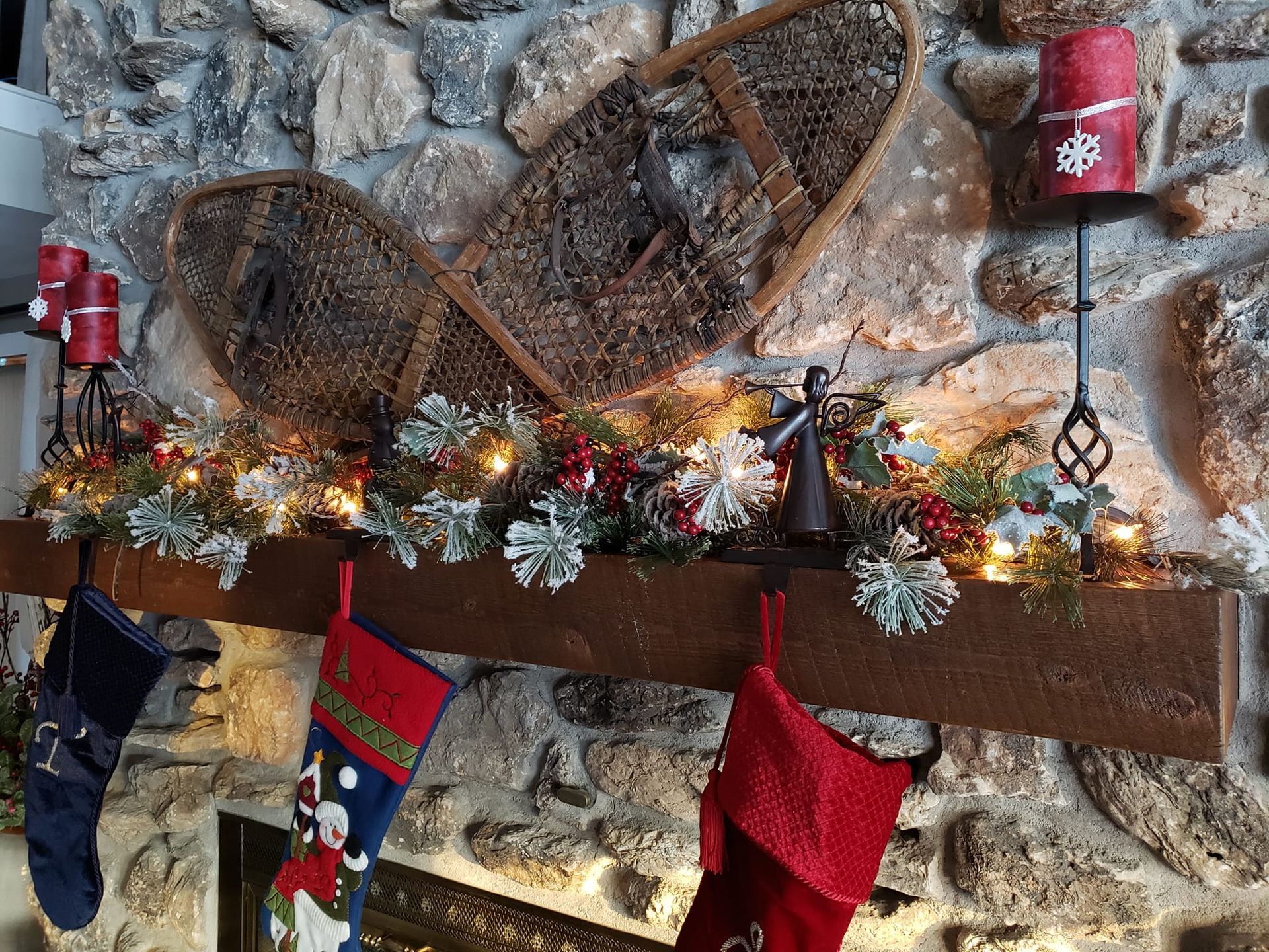 Christmas stockings are hanging on a mantle in front of a stone wall.