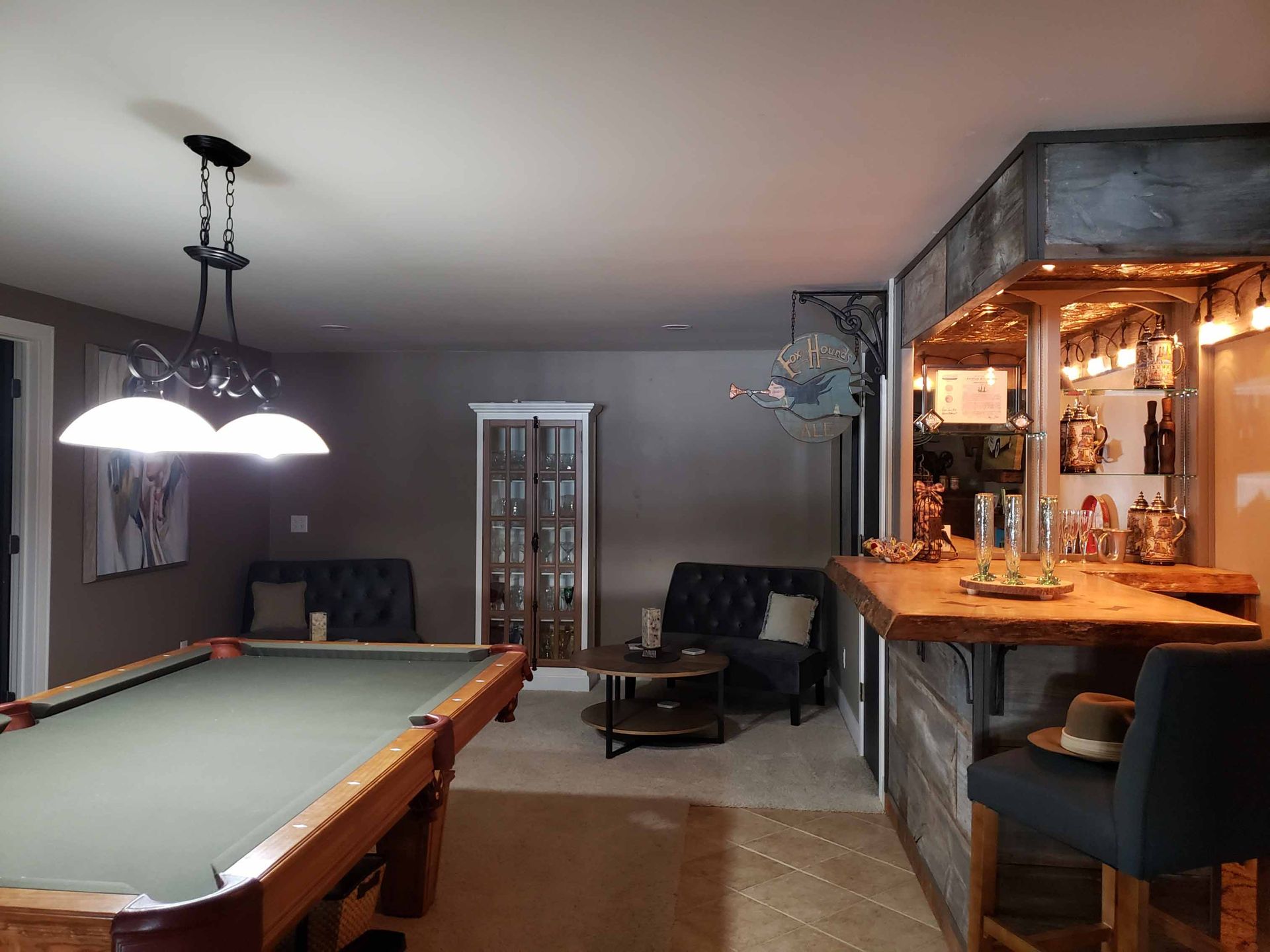 A pool table in a living room next to a bar