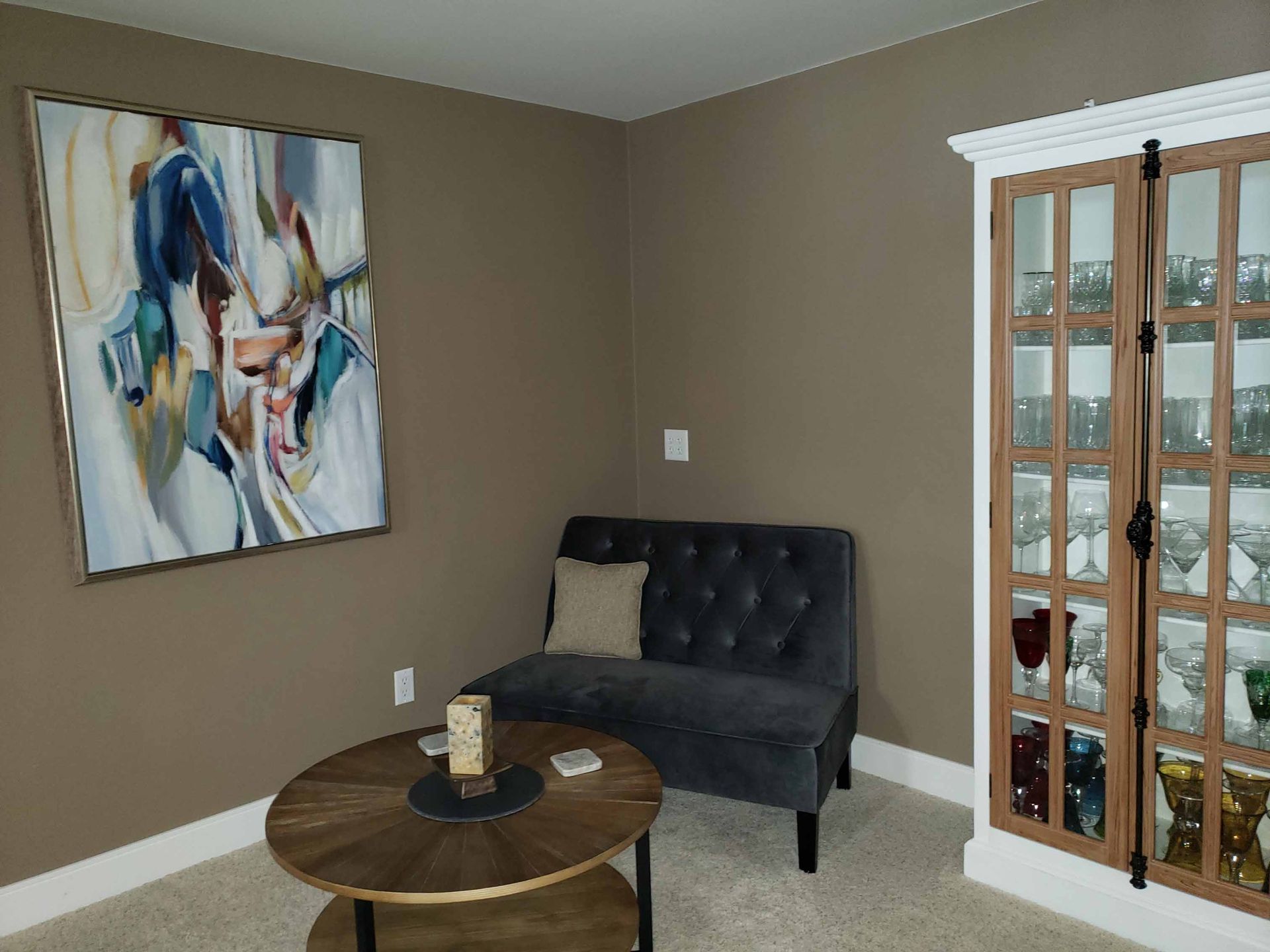 A living room with a couch , coffee table , and a painting on the wall.