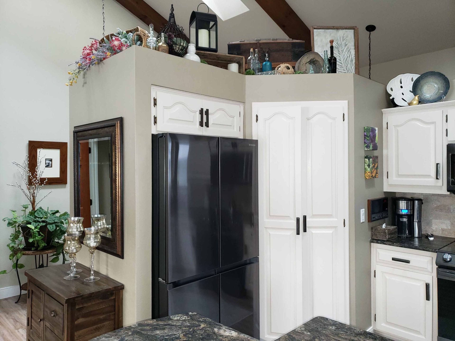 A kitchen with white cabinets and a black refrigerator
