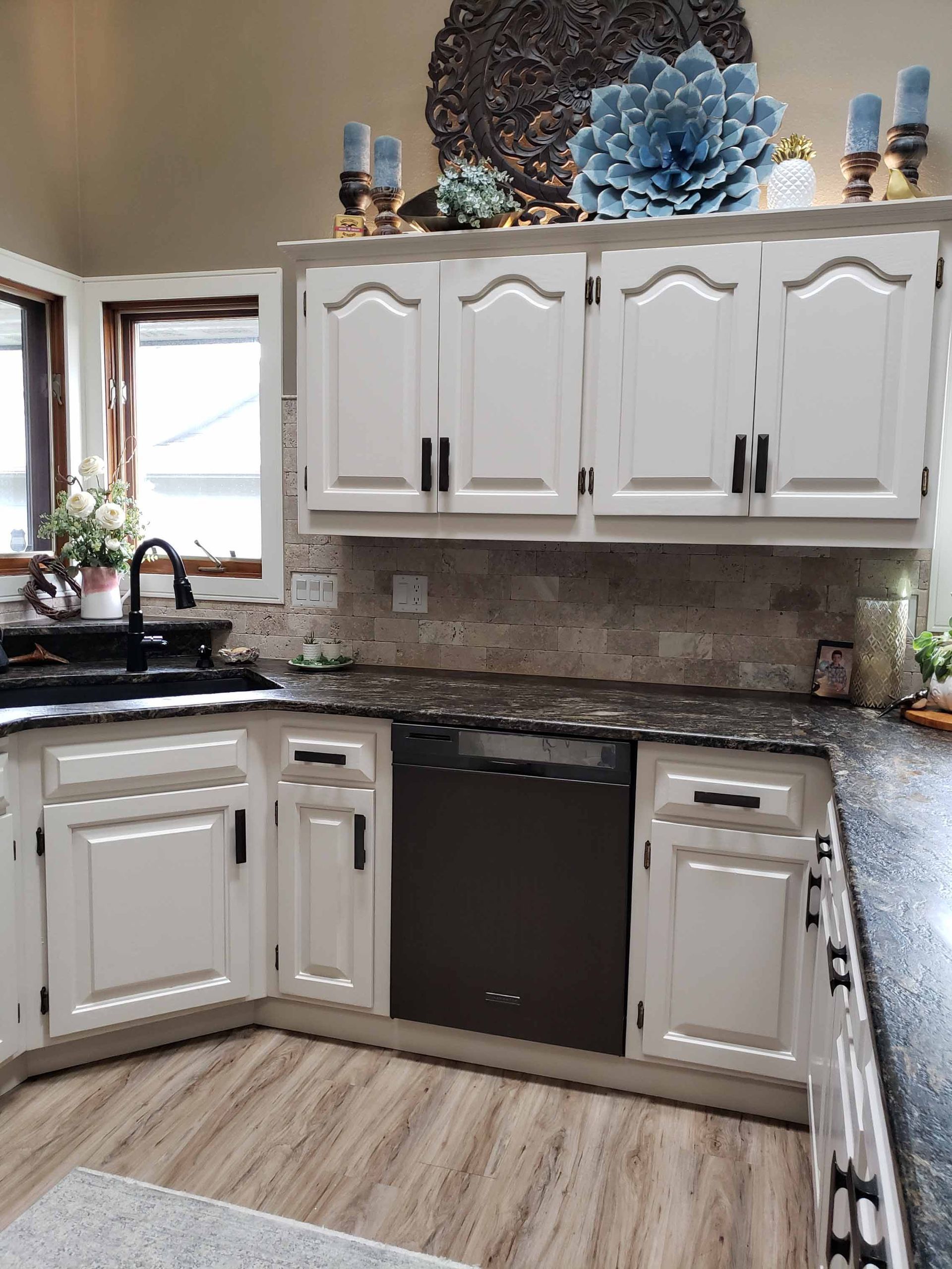 A kitchen with white cabinets and black counter tops