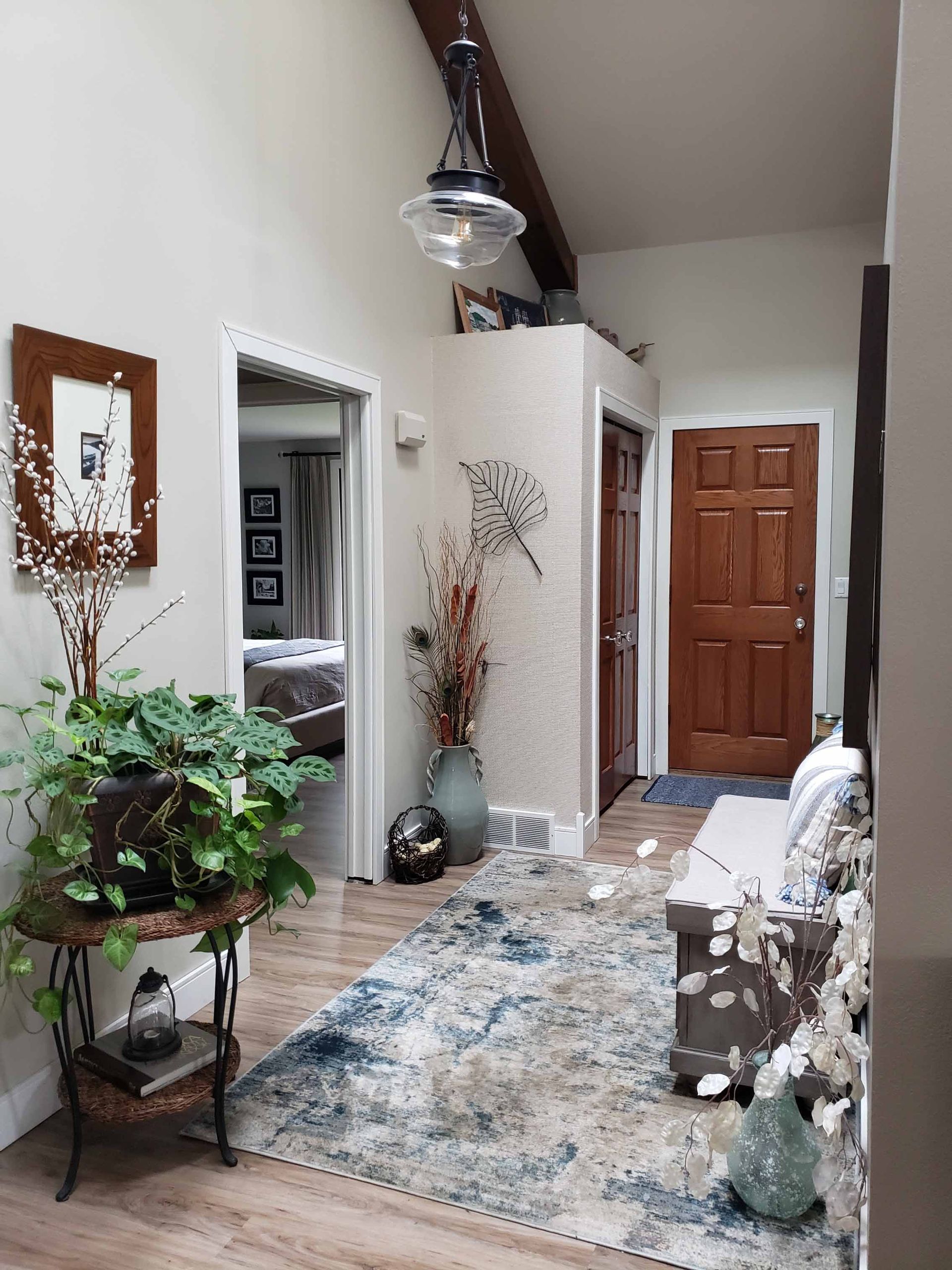 A living room with a rug , couch , chair , and plant.