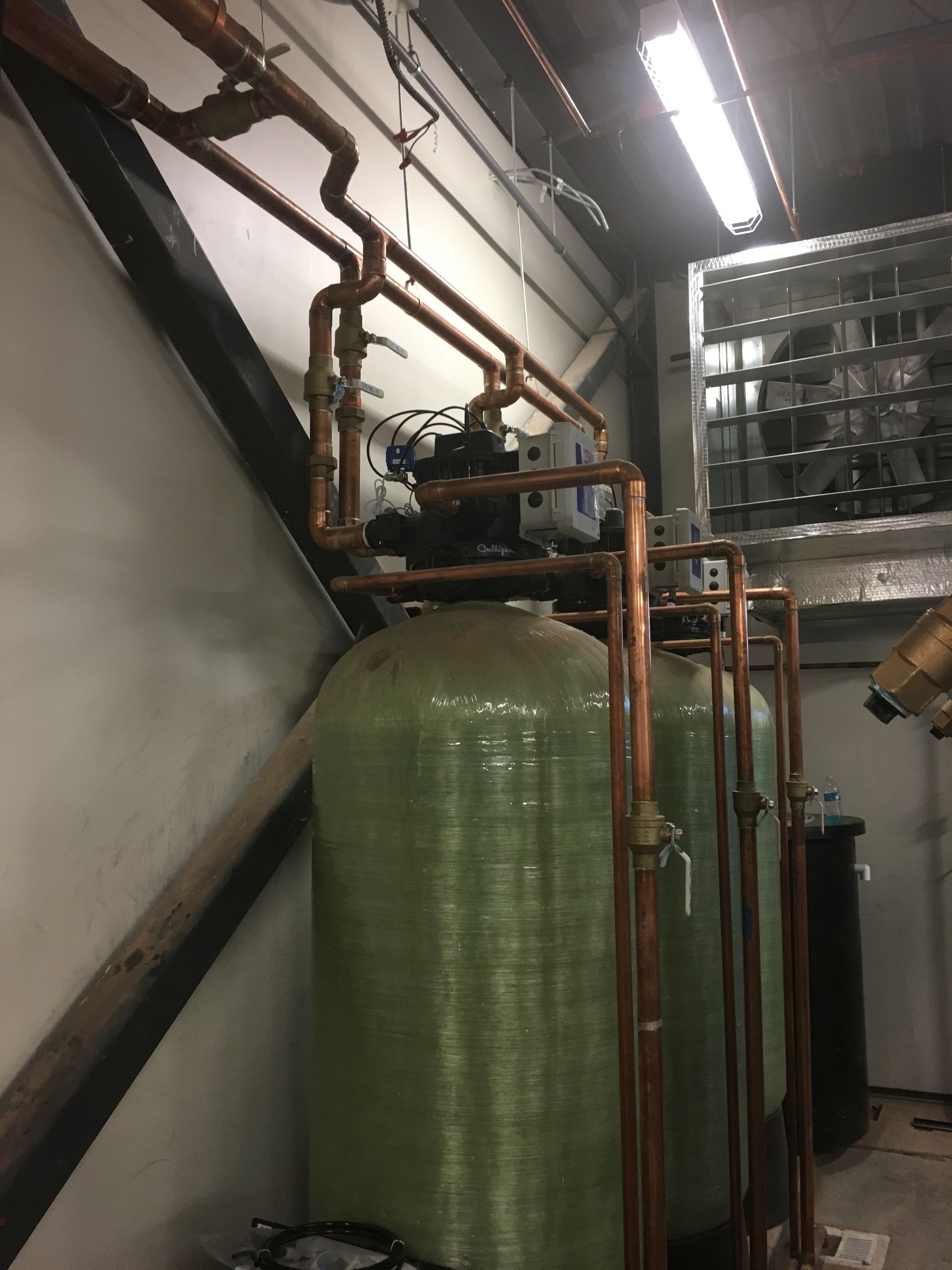 A row of green tanks with copper pipes attached to them