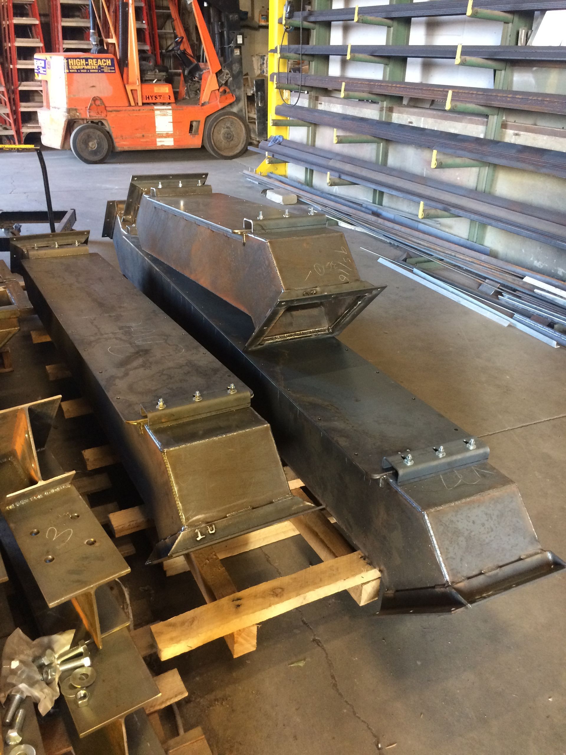 A forklift is sitting in a warehouse next to a bunch of metal pieces.