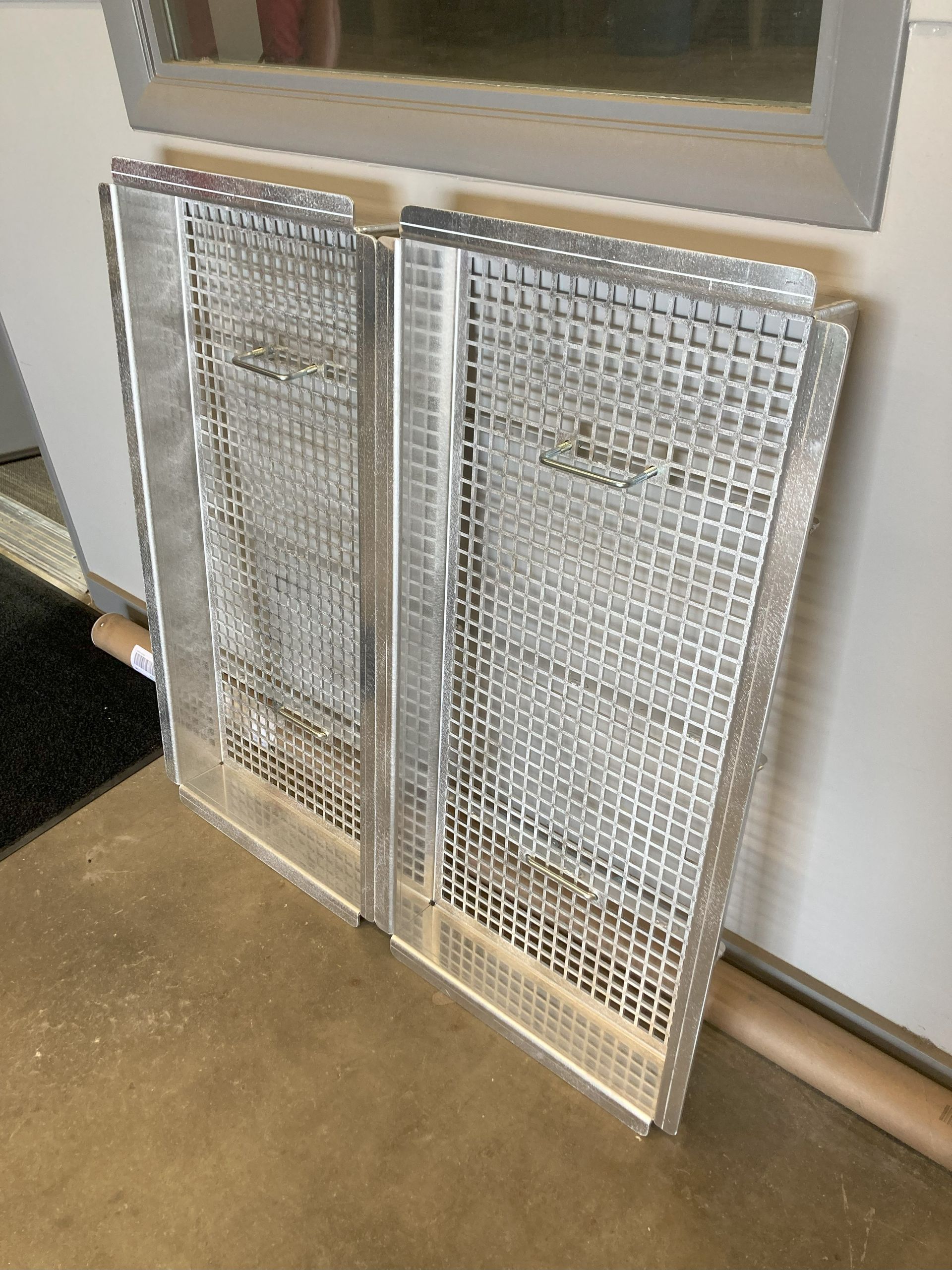 A metal fence is sitting on the floor next to a window.