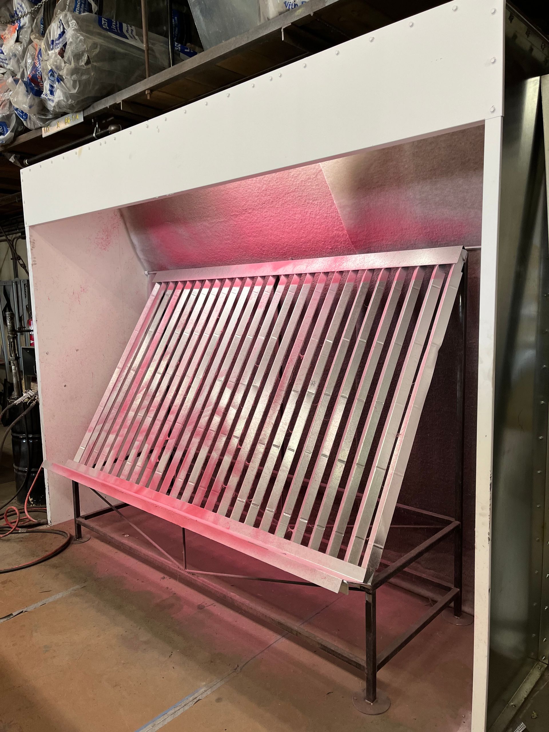 A stainless steel grill is sitting in a spray booth.