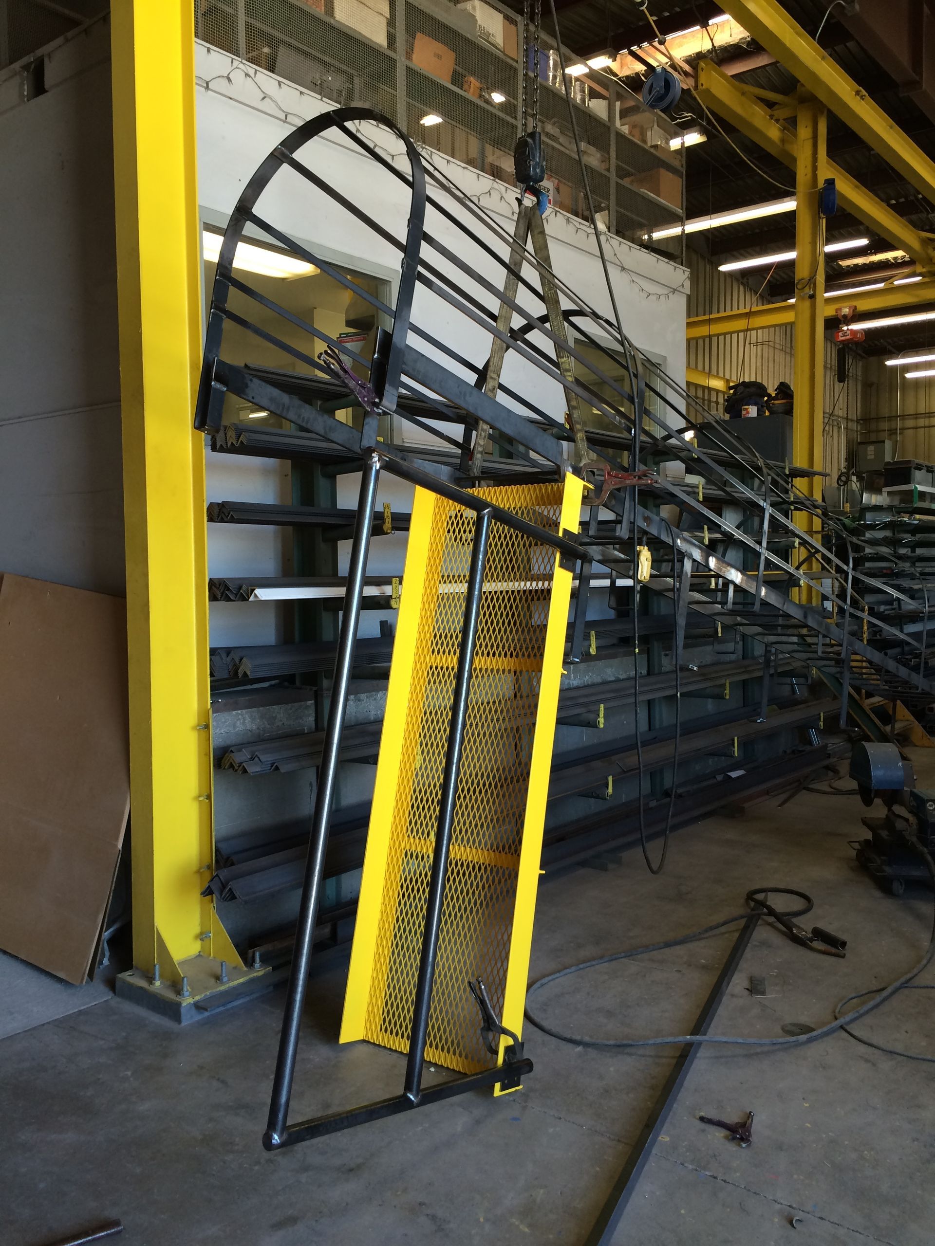 A staircase with a yellow railing is being built in a factory